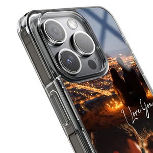 May include: Clear phone case with a printed design. The design features a silhouette of two people overlooking a city at night, with the words "I love you" in cursive. The case is made of a transparent material, allowing the phone's color to show through.