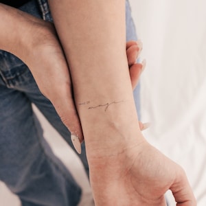 May include: A close-up of a person's wrist with a temporary tattoo that reads "Made of magic".