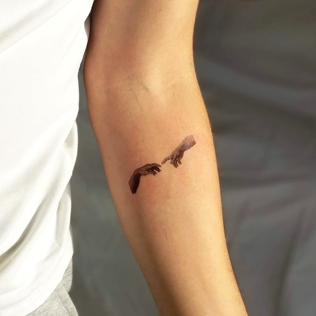 tatuaje de la creación de las manos de adam