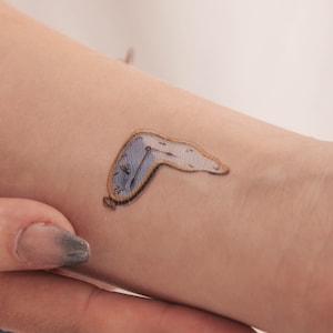 May include: A temporary tattoo of a melting clock, a classic surrealist image.