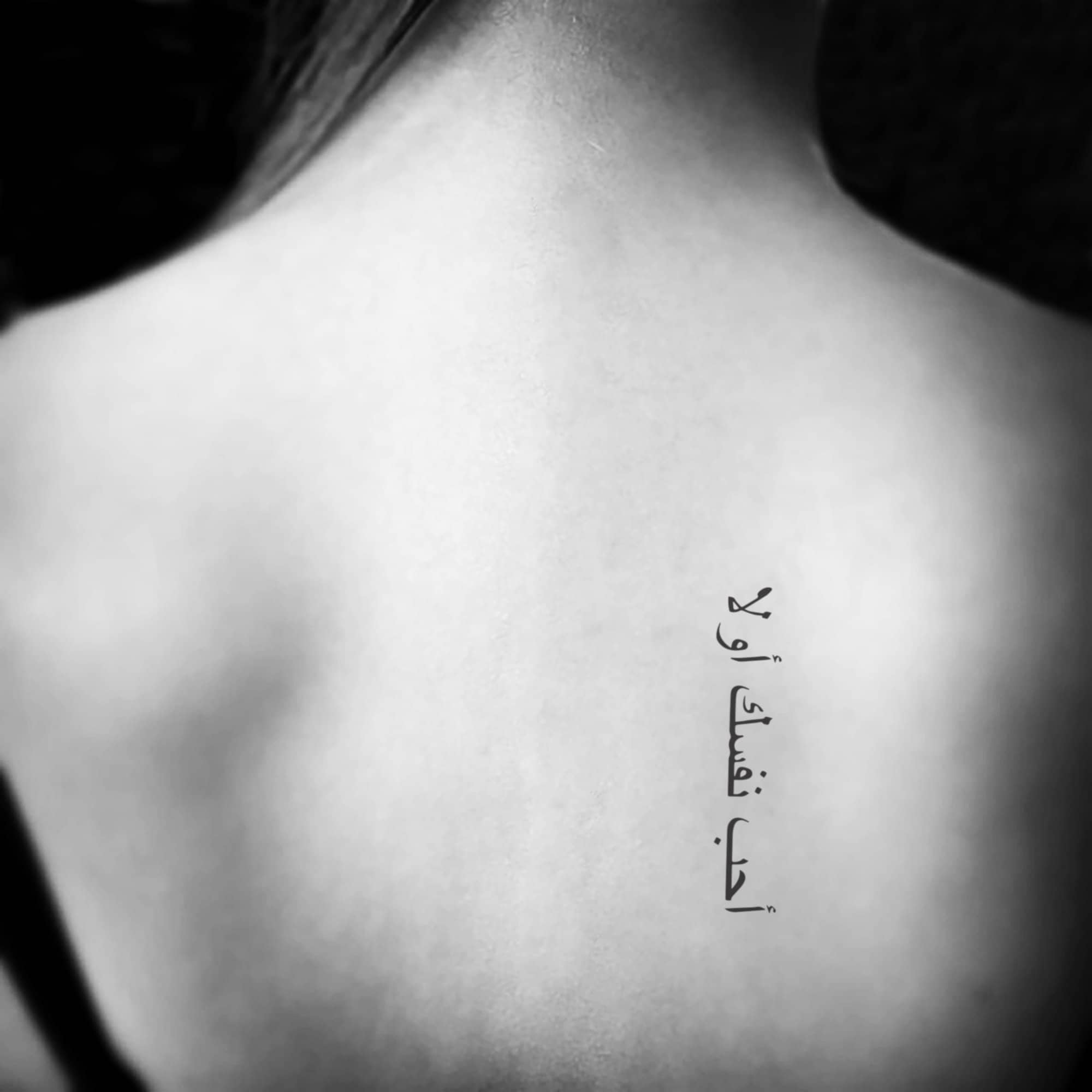 Arabic quote tattooed on the back.