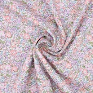 Puede incluir: Primer plano de una tela floral rosa y blanca con un patrón de pequeña escala. La tela está doblada y drapeada, mostrando la textura y el detalle de la impresión.