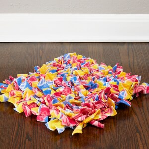 May include: A colorful dog toy made of knotted fabric in shades of red, yellow, and blue. The toy is designed to be interactive and engaging for dogs.