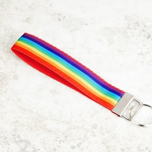 May include: A rainbow-colored key chain with a red strap and a silver key ring.