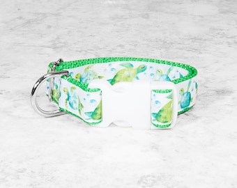 May include: A green and white dog collar with a sea turtle pattern and a white plastic buckle.