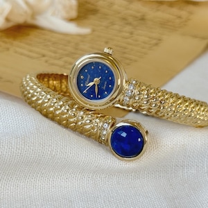 Relógio feminino vintage Vexcel em metal dourado com pedra azul, relógio com pulseira e joia