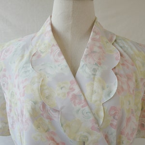 May include: A white blouse with a scalloped collar and a floral print in shades of pink, yellow, and green.