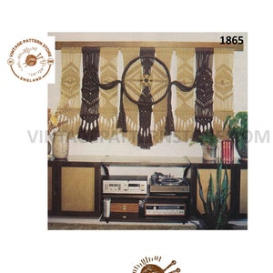 May include: A macrame wall hanging with a circular design in the center. The hanging is made of brown and beige yarn and has a fringe at the bottom. The hanging is displayed on a wall above a stereo system.
