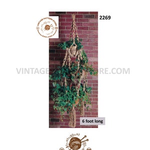 Może przedstawiać: Wiszący kwietnik wykonany z makramu z trzema doniczkami, zrobiony z naturalnego sznurka, wiszący na ceglanej ścianie. Kwietnik ma 1,83 metra długości. Obraz zawiera tekst "VINTAGE PATTERN STORE ENGLAND" i "Vintagepatternstore.com".