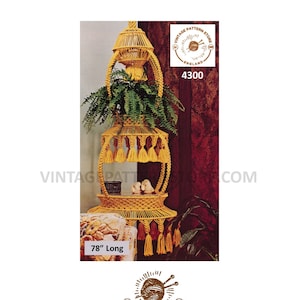 以下が含まれることがあります： 黄色のコードで作られた、3段の、78インチの長さの、マクラメのプラントハンガー。ハンガーはタッセルで飾られており、赤い壁のある部屋に吊るされている様子が示されています。