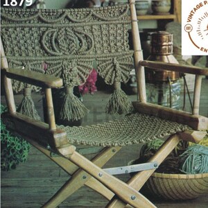 Op de afbeelding: Een houten klapstoel met een macram&eacute; zitting en rugleuning. De macram&eacute; is gemaakt van natuurlijk gekleurd koord en heeft een franje ontwerp. De stoel staat op een houten vloer.