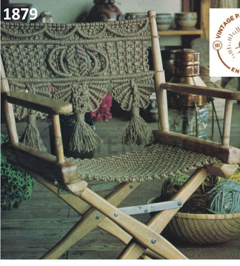Op de afbeelding: Een houten klapstoel met een macram&eacute; zitting en rugleuning. De macram&eacute; is gemaakt van natuurlijk gekleurd koord en heeft een franje ontwerp. De stoel staat op een houten vloer.