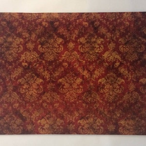 May include: A red and gold damask patterned fabric with a distressed, vintage look.
