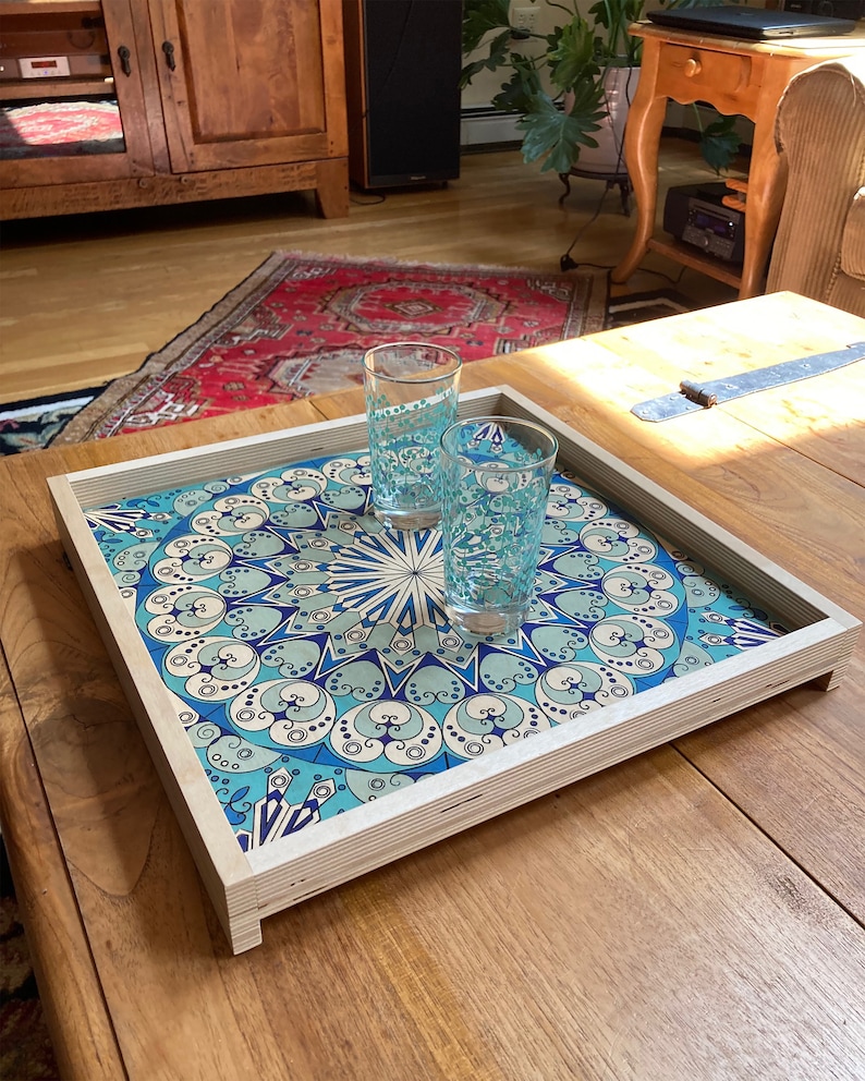 May include: A wooden serving tray with a blue and white geometric pattern. Two clear glass cups are on the tray.