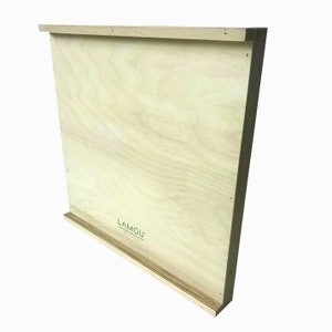 May include: A light wood-toned rectangular box with a slightly raised lip on the top and bottom. The box has a small label on the bottom that reads "LAMOU" with a website address.