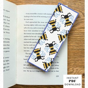 May include: A handmade bookmark featuring a pattern of pixelated bees in yellow, black, and light blue on a white background. The bookmark has a blue border and is on an open book. The text "INSTANT PDF DOWNLOAD" is visible.