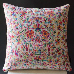 May include: A white throw pillow with a colorful floral and bird pattern. The pattern features bright colors like pink, yellow, blue, green, and red. The pillow is made of a soft, comfortable fabric.
