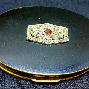 Art Deco black enamel and brass powder compact with a rhinestone center and the original puff. #167