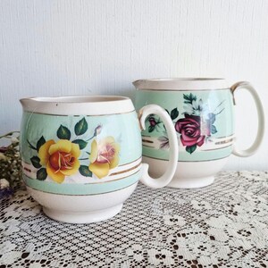 May include: A white ceramic mug with a black handle and the text "But First, Coffee" in a bold, black font. The mug is set against a blurred background, suggesting a cozy setting.