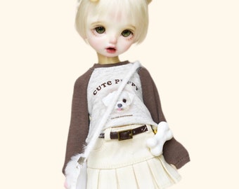 May include: A doll with blonde hair in pigtails wearing a brown and white shirt with the text "Cute Puppy" and a white skirt. The doll is wearing white socks and light blue sneakers.
