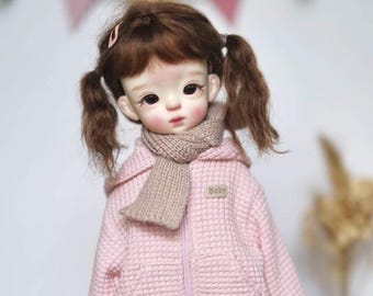 May include: A pink knitted hooded jacket with a zipper closure and a brown knitted scarf. The jacket has a patch on the front that says "Baby".