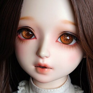 May include: A doll with long brown hair wearing a white dress with a black bow and a pearl necklace. The doll has brown eyes and a light complexion. The doll's name is "Salafina" written on the bow.
