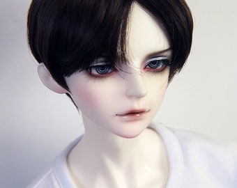 May include: A doll with short, dark brown hair styled in a blunt cut. The doll has pale skin, blue eyes, and is wearing a white t-shirt with the word "Salafina" printed on the front.