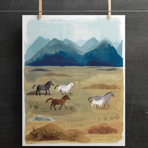 Puede incluir: Impresi&oacute;n en acuarela de un paisaje con una manada de caballos en un campo, con un tel&oacute;n de fondo de monta&ntilde;as azules. Los caballos son de varios colores, incluyendo marr&oacute;n, gris y blanco. La impresi&oacute;n est&aacute; sujeta con pinzas de madera.