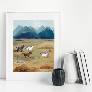 Puede incluir: Una impresi&oacute;n art&iacute;stica enmarcada que presenta un paisaje con caballos corriendo. La obra de arte representa una manada de caballos en tonos marrones, grises y blancos, sobre un fondo de monta&ntilde;as azules y un campo beige. La impresi&oacute;n est&aacute; en un marco blanco.