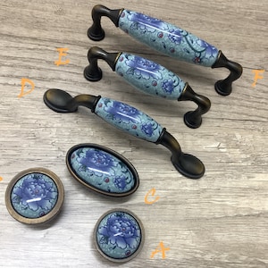 Puede incluir: Conjunto de seis pomos de armario de estilo antiguo con diseños florales azules y blancos. Los pomos tienen un acabado en bronce y están disponibles en varios tamaños.