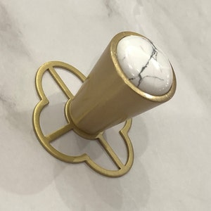 May include: Gold cabinet knob with a white marble top and a decorative, openwork base.