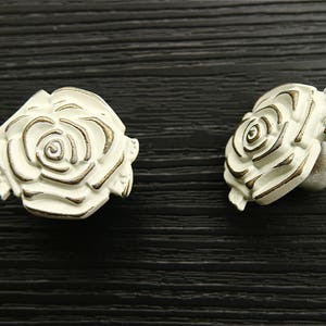 May include: Two white ceramic rose-shaped drawer pulls with gold accents.