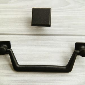 Może przedstawiać: Czarny zestaw okuć do szafek z kwadratową klamką i prostokątnym gałką.