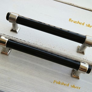 May include: Two black cabinet pulls with silver finishes. The top pull has a brushed silver finish and the bottom pull has a polished silver finish. The text "Brushed silver" is above the top pull and the text "Polished silver" is below the bottom pull.