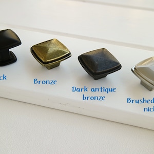 Peut inclure: Quatre boutons de cabinet carrés dans différentes finitions : noir, bronze, bronze antique foncé et nickel argent brossé.