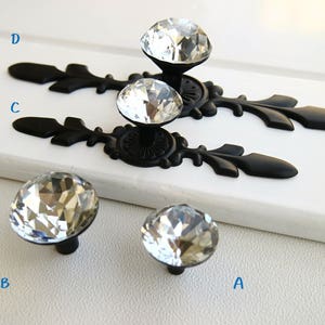 May include: Four black cabinet knobs with crystal diamond-shaped handles. The knobs have a decorative, ornate design.