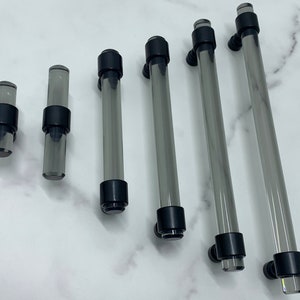 May include: Set of six clear glass cabinet pulls with black metal end caps. The pulls are of varying lengths.