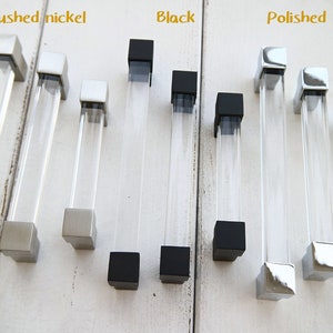 Pode incluir: Um conjunto de dez puxadores de armário de acrílico transparente com bases quadradas em acabamentos níquel escovado, preto e prata polida.
