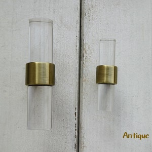 May include: Two clear acrylic cabinet pulls with antique bronze metal rings. The pulls are different sizes.