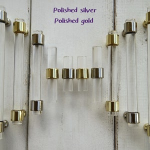 May include: A set of clear acrylic cabinet pulls with polished silver and gold accents. The pulls are available in two sizes.
