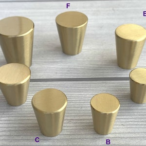 Peut inclure: Dix boutons de porte en or, de différentes tailles. Les boutons sont en forme de cône avec une finition lisse et brossée.