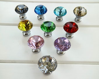 Puede incluir: Surtido de diez pomos de cristal para armarios en varios colores, incluyendo transparente, azul, verde, rojo, amarillo, morado y rosa. Cada pomo presenta una forma de diamante facetado y una base plateada.