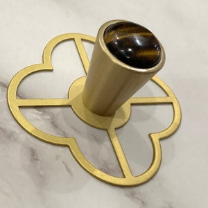 May include: Gold metal decorative knob with a tiger's eye stone top. The knob has a four-leaf clover design.