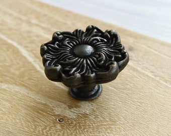 May include: A black metal cabinet knob with a decorative floral design.