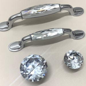 May include: Two silver cabinet knobs with faceted crystal inserts and two smaller crystal knobs.