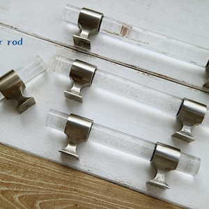 May include: Four clear acrylic cabinet pulls with silver metal bases. The pulls are different lengths. The text "Bigger rod" is visible in the image.