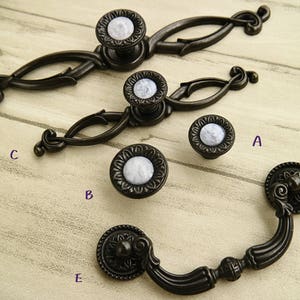 May include: Five antique-style cabinet knobs with a black finish and white porcelain inserts. The knobs are in various styles, including a pull handle and a traditional round knob.
