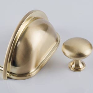 Peut inclure: Deux boutons de porte en or, l'un est rond et l'autre est incurvé en forme de coupe.