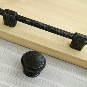 May include: Black metal cabinet hardware with a distressed finish. The hardware includes a pull handle and a knob.