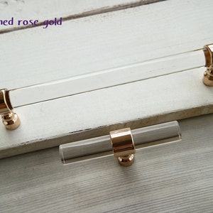 May include: Two clear acrylic cabinet pulls with polished rose gold metal accents. The larger pull is approximately 15cm long and the smaller pull is approximately 7.5cm long.